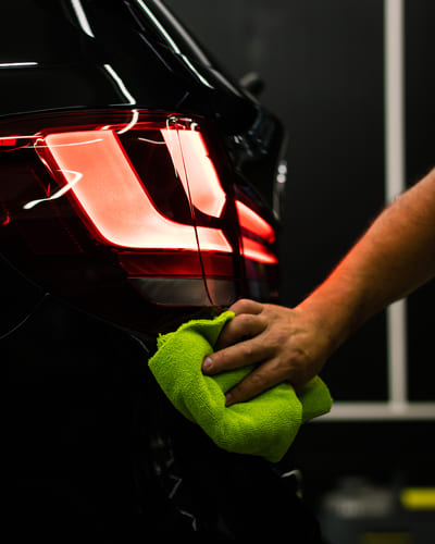 selective focus shot man cleaning car s back headlight with microfiber cloth